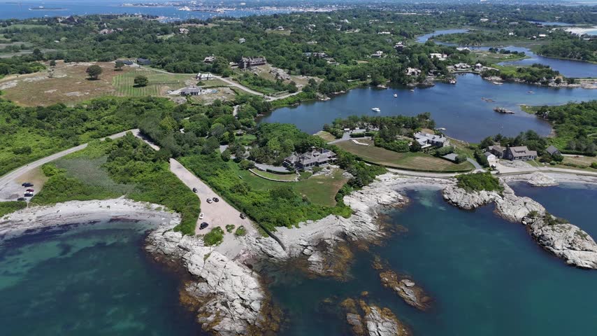 High-altitude drone perspective of sprawling historic mansions situated on the lush green rocky peninsulas of Newport, Rhode Island, overlooking the Atlantic Ocean