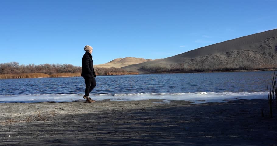 Woman walking along lake at Bruneau Dunes State Park, Idaho