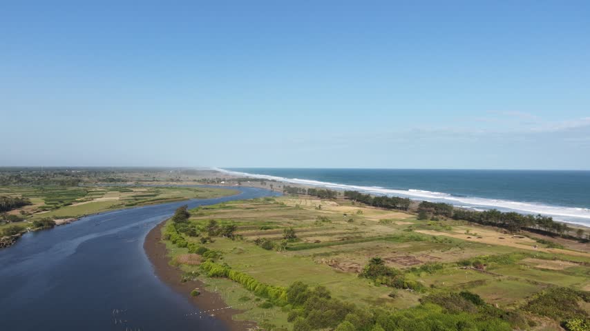 Aerial coastal landscape with marshland road and wide ocean under blue sky