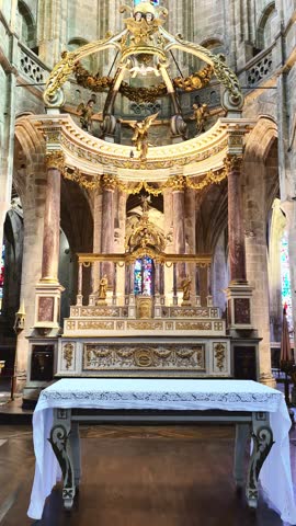 Elaborate golden altar inside a historic gothic Basilica Saint-Sauveur in Dinan, France, with stained glass windows and religious statues. Ideal for editorial travel articles, religious history publications, and architectural photography.