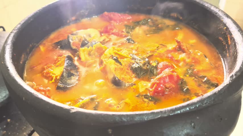 Authentic Brazilian Surubim fish Moqueca boiling in a traditional clay pot. A rich, steaming seafood stew with tomatoes, herbs, and dendê oil.