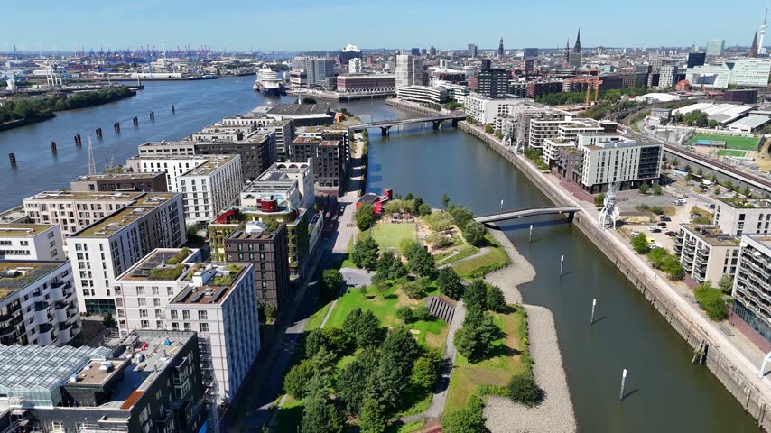 Aerial view of Baakenhafen in the Hafencity featuring modern residential architecture, green park spaces, and waterfront walkways along the river in Hamburg, Hamburg, Germany.
