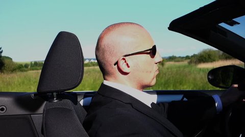 a business man is driving a convertible car in a landscape, perspective side view