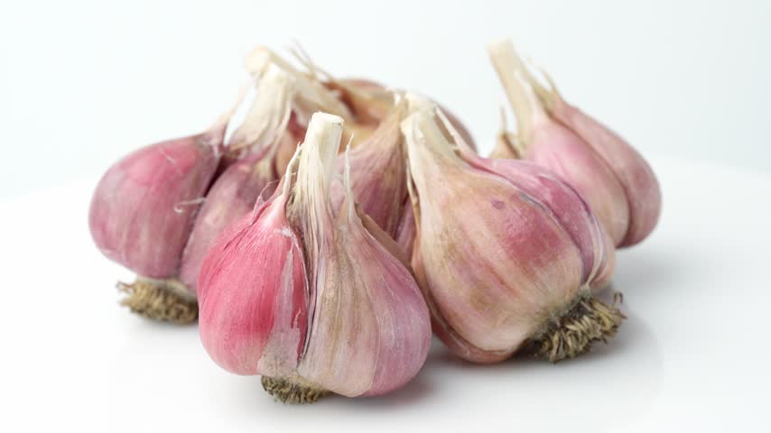 Unpeeled fresh organic garlic bulbs rotating in close up view. Harvesting and agriculture. Farming. Vegetables.