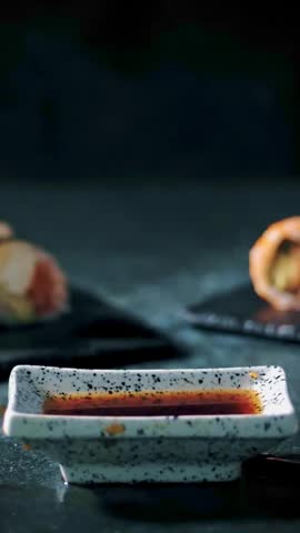 Traditional Japanese food. close-up. Super slow motion video of fresh sushi falling into soy sauce. Sushi Rolls at sushi bar or restaurant.