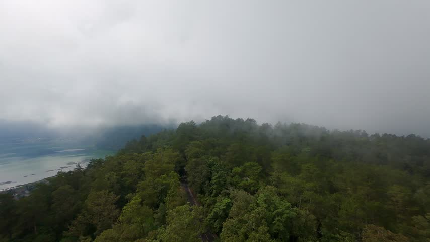 Aerial View of Forested Ridge Near Lake Batur Covered by Low Clouds, Atmospheric Tropical Mountain Landscape in Bali.
