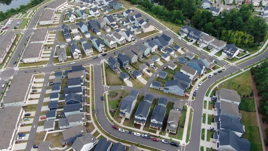 Drone forward tracking shot showing a high angle perspective of residential housing development, master planned neighborhood streets, and family homes near Holding Lake in a growing suburban community.