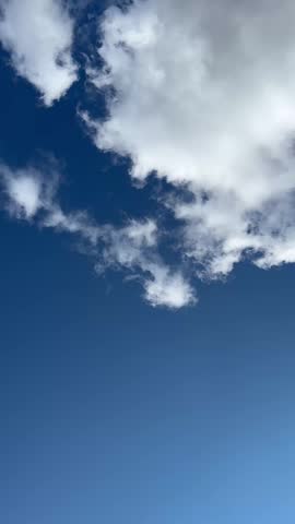White cumulus clouds drifting across a bright blue sky on a sunny day. Natural atmospheric scene suitable for weather, nature, environment, and peaceful outdoor backgrounds.