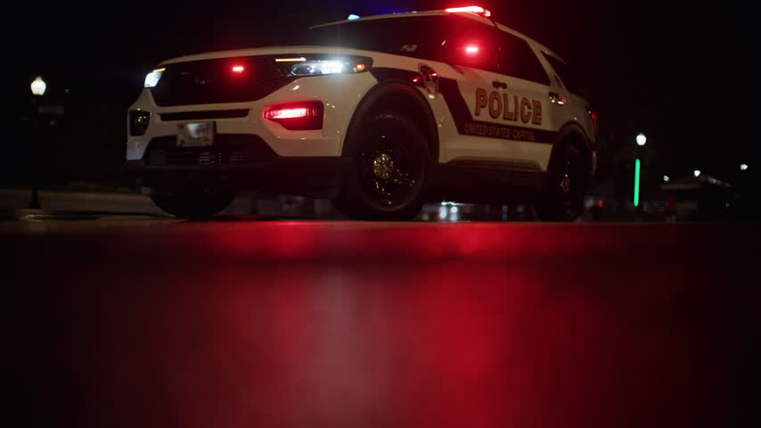 Police car with red and blue lights. Federal police vehicle with emergency lights. Police SUV from low angle view. United States Capitol police vehicle at night.