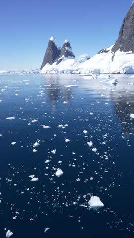 Antarctica Icy Bits, Floating Ice, Epic Landscape of Mountains, Icebergs, Snow, Glaciers, Reflections. Cruise Ship in Bismark Strait. Vertical Video.