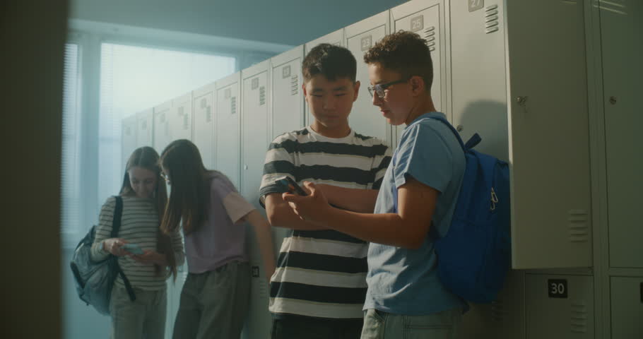 School Friends Gathers around Smartphone near Lockers, Laughing Reacting Together as Two Girls Join Boys to Watch Entertaining Content. Concept of Friendship, Social Connection, Digital Communication.