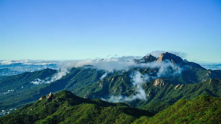 A 4K time-lapse video of the summer morning landscape of Dobongsan Mountain, looking towards cloud-covered Bukhansan Mountain near Dobong-gu, Seoul, South Korea.
