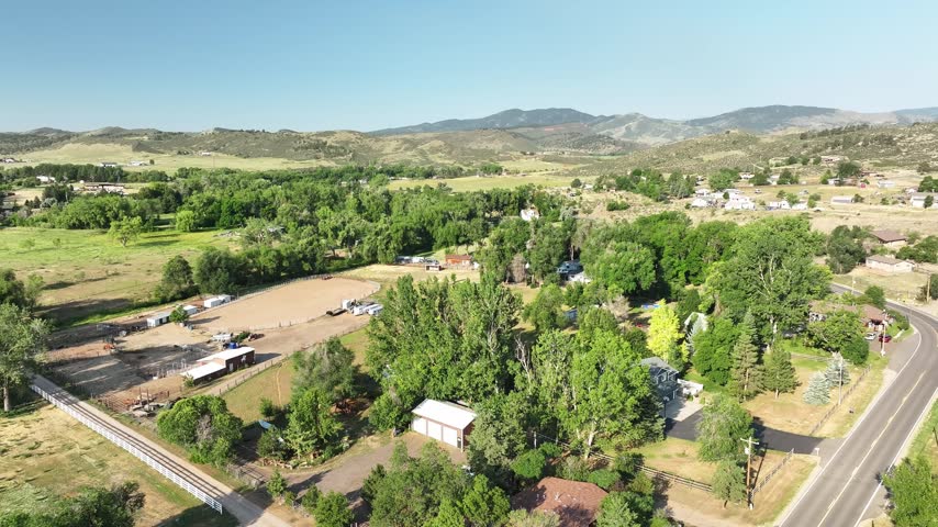 High angle shot overlooking a large white barn and rural estate nestled near the front range foothills of Colorado.