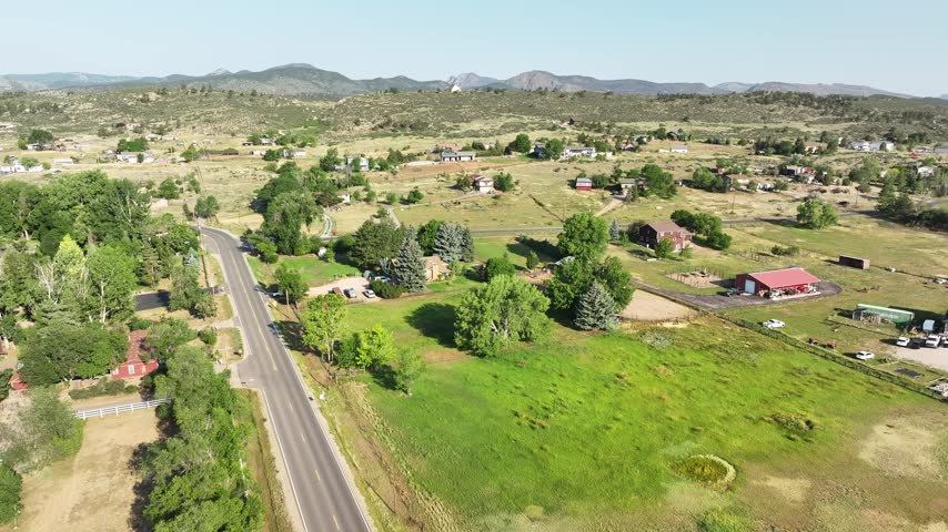 High altitude scenic shot looking over ranch-style homes, barns, and dirt roads bordering the front range foothills.