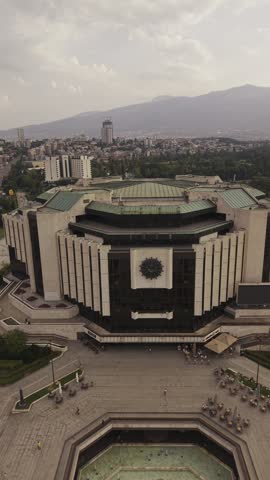 SOFIA, BULGARIA – AUGUST 18, 2026: Aerial drone view of the National Palace of Culture and its fountains in central Sofia, with Vitosha Mountain and the city skyline visible in the background during a summer evening