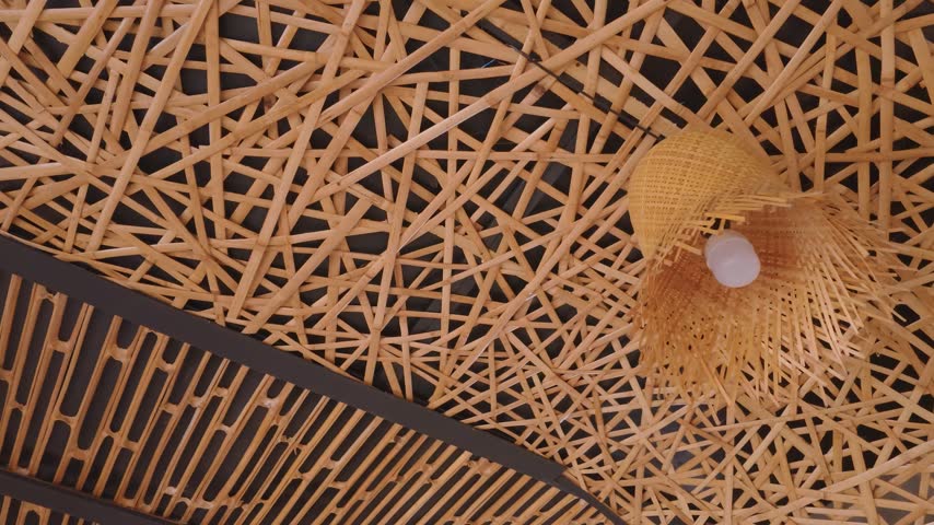 Intricate woven bamboo ceiling design with a hanging lamp fixture.