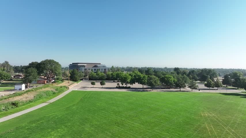 Bright blue sky drone clip capturing vibrant community parkland and academic landscapes in Northern Colorado, perfect for concepts on education, youth, and wellness.