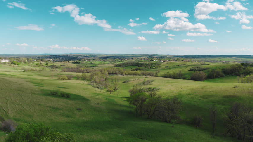 Aerial of bright blue sky and cumulus clouds over green countryside near Mandan, North Dakota, with rolling grassland.