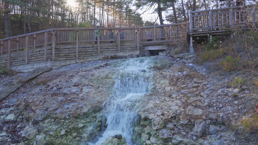 Hot Spring Water Flowing Down Rocky Slope with Wooden Walkway in Kusatsu, Japan