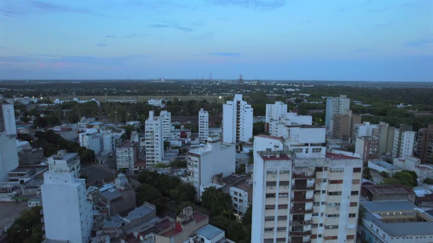 4K drone aerial view of La Plata, Buenos Aires, Argentina at sunset. Urban skyline, buildings and streets illuminated by warm evening light across the city.