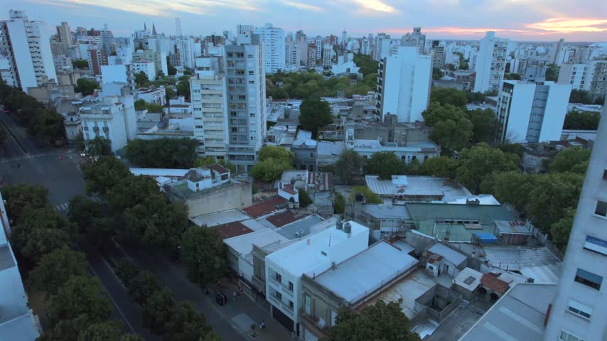 4K drone aerial view of La Plata, Buenos Aires, Argentina at sunset. Urban skyline, buildings and streets illuminated by warm evening light across the city.