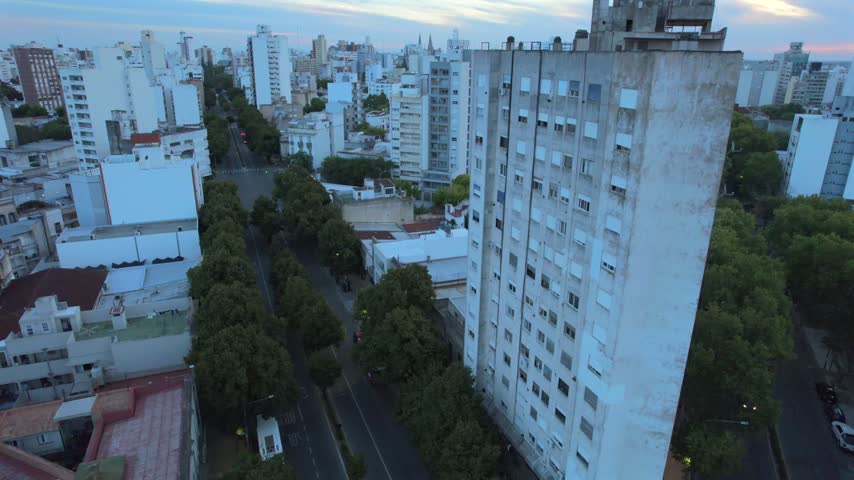 4K drone aerial view of La Plata, Buenos Aires, Argentina at sunset. Urban skyline, buildings and streets illuminated by warm evening light across the city.