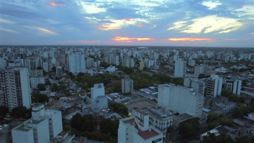 4K drone aerial view of La Plata, Buenos Aires, Argentina at sunset. Urban skyline, buildings and streets illuminated by warm evening light across the city.