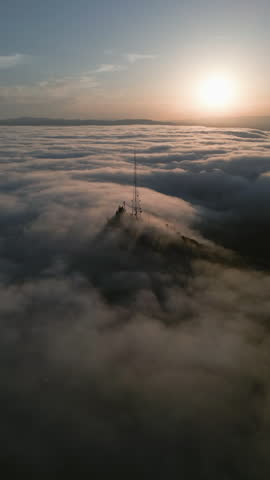 Aerial portrait shot toward a telecommunications tower, misty sunrise in LA