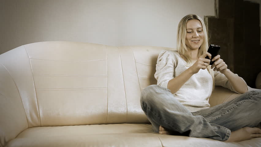 Beautiful girl on sofa with the laptop, speaking by phone