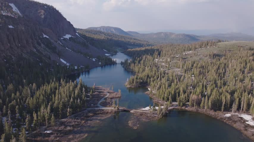 Aerial drone view of Twin Lakes in Mammoth Lakes, California, showcasing scenic alpine lakes, rugged mountain ranges, and dense pine forests during a clear summer day