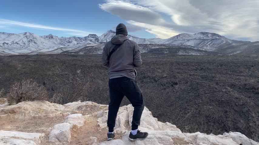 Young Latino man photographing mountains, captured in a cellphone-recorded video as he documents the landscape and enjoys an outdoor photography moment.