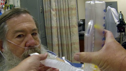 Medical mature man with beard breathing after surgery. Man in hospital recovery room after major serious arm reconstruction surgery. Breathing equipment help raise oxygen level. Arm and hand bandaged