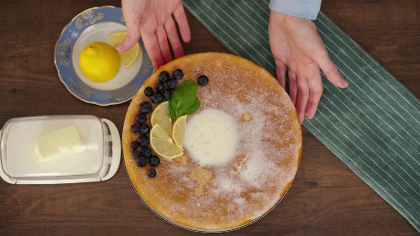 Hand presenting finished lemon blueberry cake in cozy kitchen