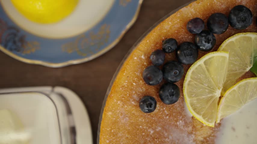 Hand presenting finished lemon blueberry cake in cozy kitchen