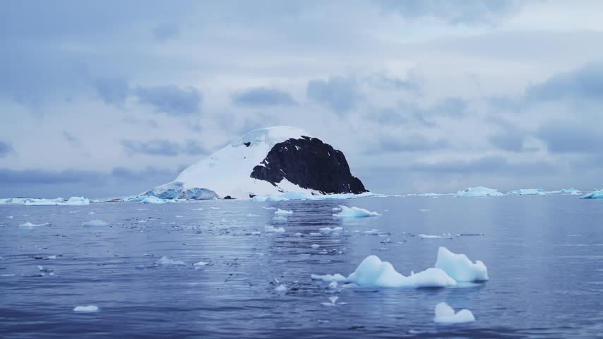 Aerial drone shot of Beautiful Antarctica Scenery at Sunset with Dramatic Clouds and Sky, Southern Sea and Beautiful Mountains on Rugged Antarctic Peninsula while on a Zodiac Boat Trip Tour Excursion