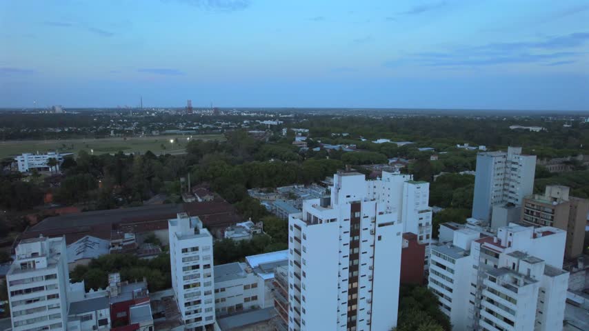 4K drone aerial view of La Plata, Buenos Aires, Argentina at sunset. Urban skyline, buildings and streets illuminated by warm evening light across the city.