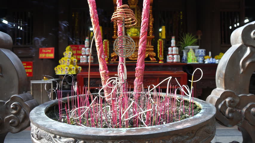 Static shot of incense burning in ornate pot at temple entrance during daytime