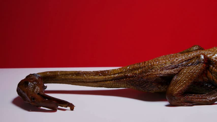 Whole roasted duck with head on white table against red background traditional holiday feast meal festive dinner dish meat poultry food