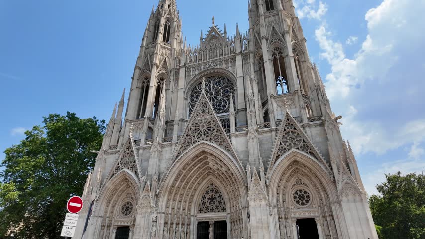 Sunny view of the Abbatiale Saint-Ouen in the historic center of Rouen, featuring soaring Gothic towers and intricate stonework.