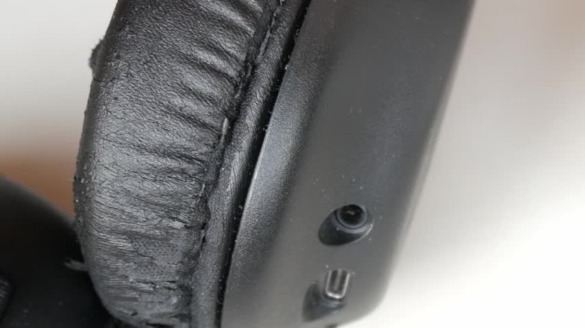 Two sets of over-ear headphones, one black and another white on white table surface.