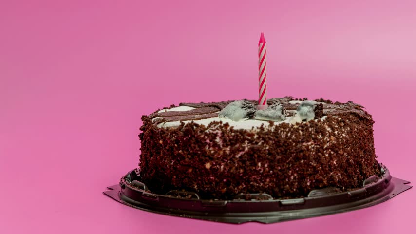 A cake with a candle burns brightly at a birthday party.