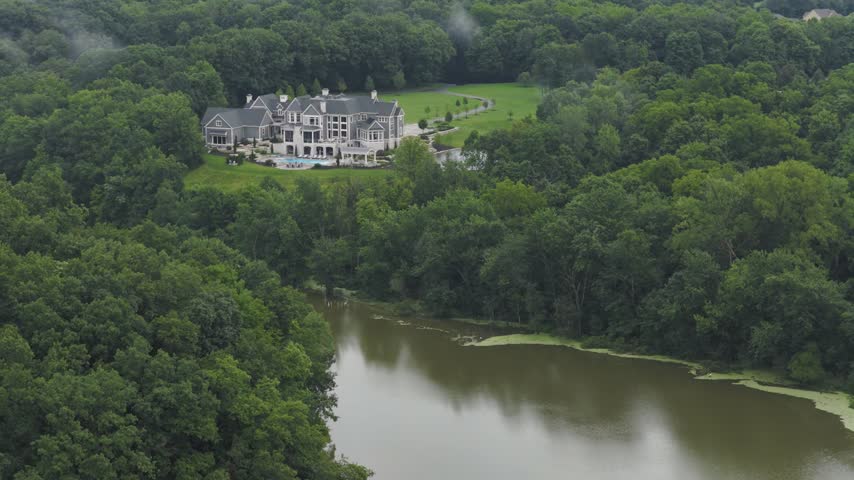 Drone aerial of big house mansion home and upper class income residential living along big walnut creek water river way outside Columbus and Galena, OH in Ohio landscape with trees, woods, and forest