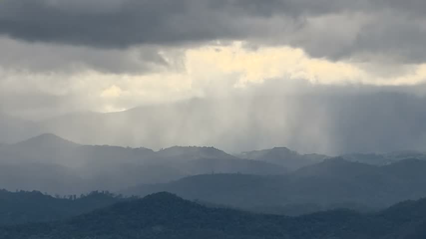 Timelapse of dramatic sunbeams and cloud movement over misty mountain range, full HD stock footage