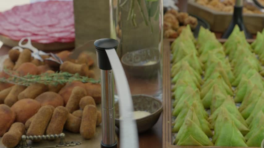 Fly deterrent fan turning above trays of fried croquettes samosas and cured ham