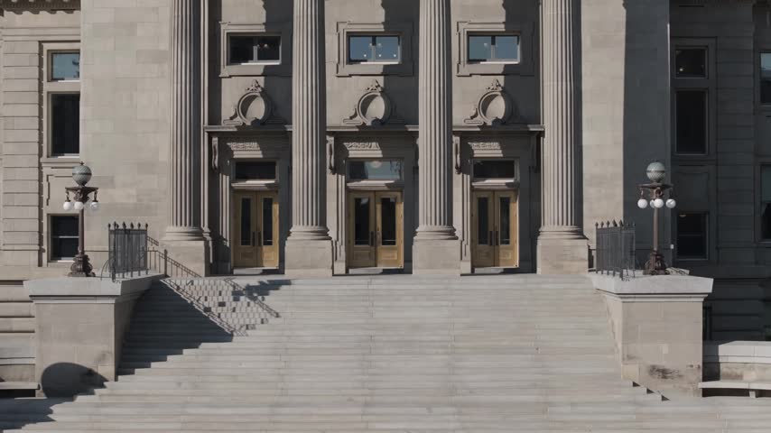Rising shot of the Idaho state capital building in Boise idaho as seen from a drone. view starts at the bottom stair level but them goes up to the dome at the top showing mountains in the background