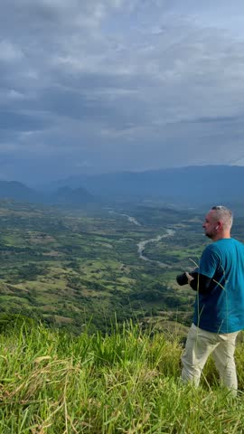 Travel Photographer Taking Pictures of Scenic Mountain Valley Landscape with River Under Dramatic Cloudy Sky
