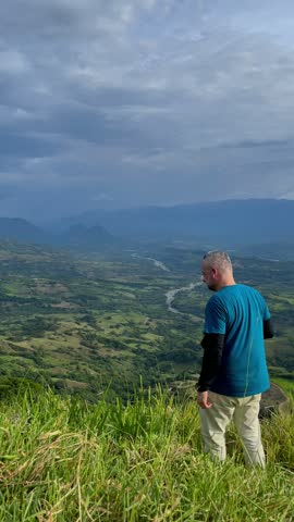 Travel Photographer Taking Pictures of Scenic Mountain Valley Landscape with River Under Dramatic Cloudy Sky