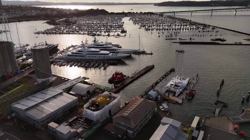 Luxury superyachts in Westhaven Marina and Auckland Harbour Bridge in Auckland, New Zealand. Aerial drone view