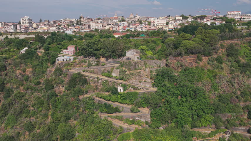 Epic aerial of Chiazzette trail to Santa Maria la Scala, a fishing village surrounded by volcanic cliffs near Mount Etna in Acireale, Catania, Sicily, Italy, a popular destination on the Ionian coast