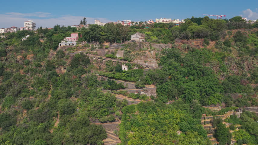 Wide aerial of Chiazzette trail to Santa Maria la Scala, a fishing village surrounded by volcanic cliffs near Mount Etna in Acireale, Catania, Sicily, Italy, a popular destination on the Ionian coast